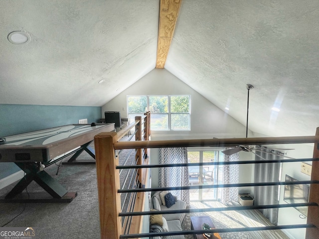 unfurnished office featuring carpet, lofted ceiling with beams, and a textured ceiling