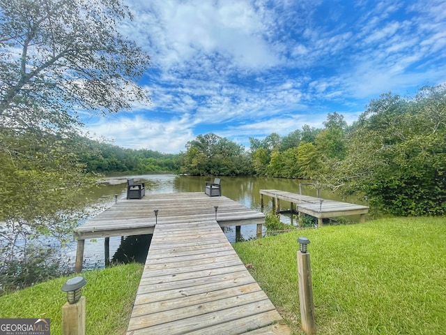 view of dock with a lawn and a water view