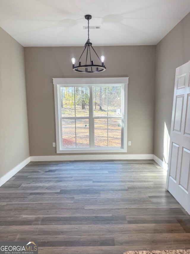 unfurnished dining area with dark hardwood / wood-style floors and a chandelier