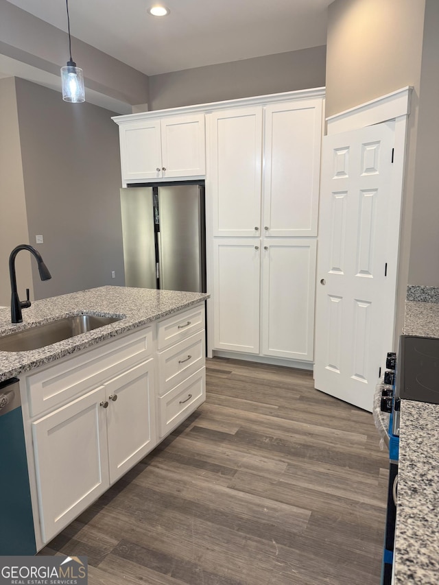 kitchen with sink, appliances with stainless steel finishes, white cabinetry, dark hardwood / wood-style floors, and light stone countertops