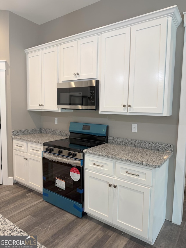 kitchen with light stone counters, dark wood-type flooring, stainless steel appliances, and white cabinets