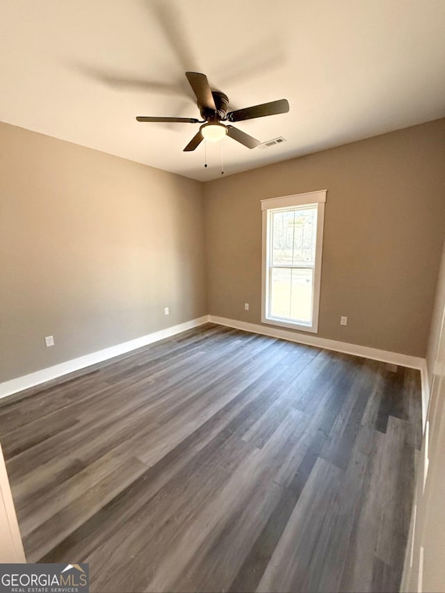 empty room with ceiling fan and dark hardwood / wood-style flooring