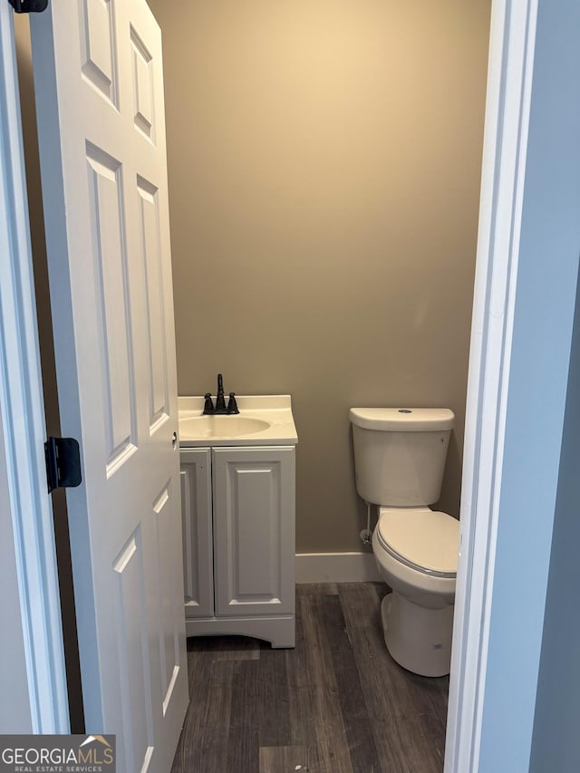 bathroom with wood-type flooring, toilet, and vanity