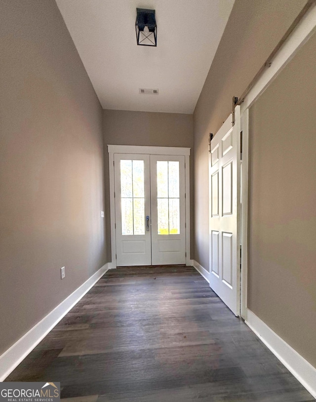 entryway with dark hardwood / wood-style floors, a barn door, and french doors