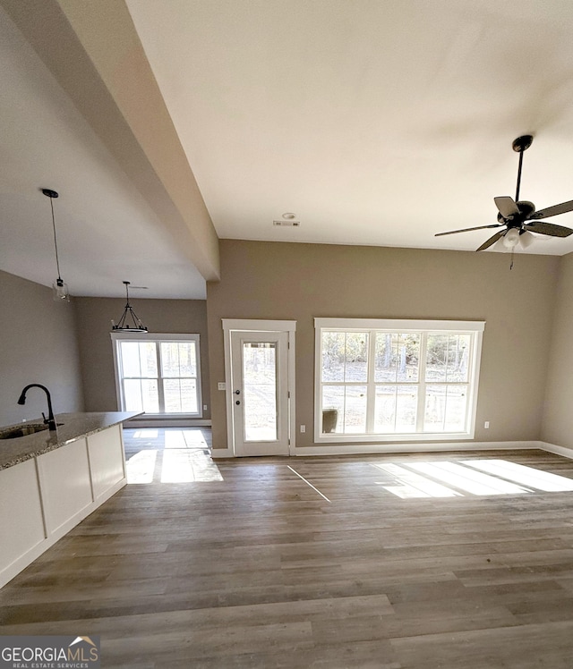 unfurnished living room with ceiling fan, wood-type flooring, and sink