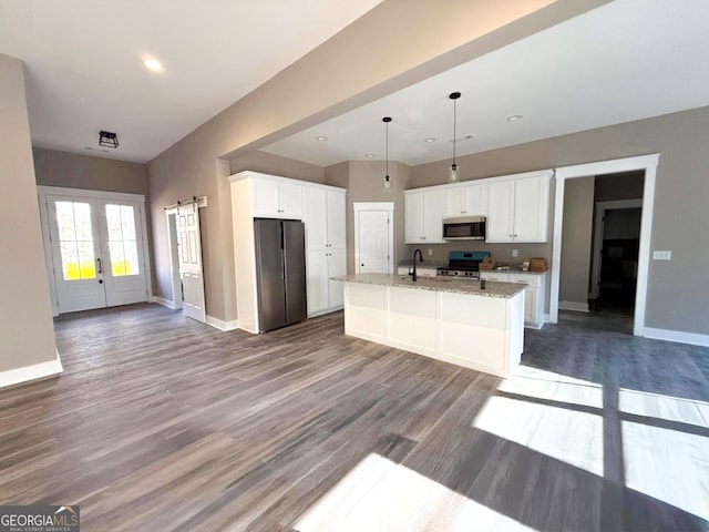 kitchen with a barn door, white cabinetry, appliances with stainless steel finishes, and an island with sink