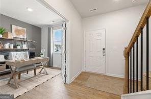 foyer with light wood finished floors, stairway, and baseboards