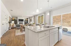 kitchen with an island with sink, open floor plan, light wood-type flooring, white cabinetry, and a sink