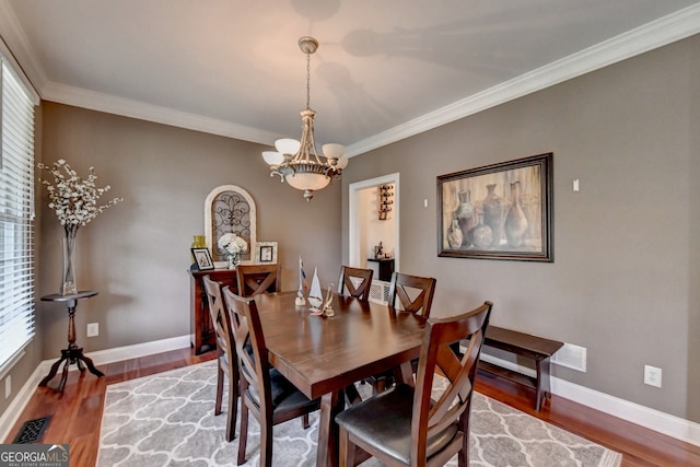 dining room featuring a notable chandelier, ornamental molding, and hardwood / wood-style flooring