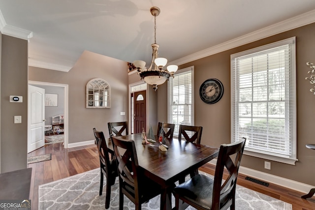 dining room with a notable chandelier, hardwood / wood-style flooring, and crown molding