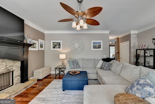 living room featuring ceiling fan, a fireplace, crown molding, and wood-type flooring