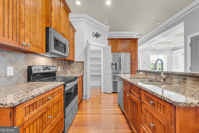 kitchen with sink, a center island with sink, light hardwood / wood-style flooring, stainless steel appliances, and decorative backsplash