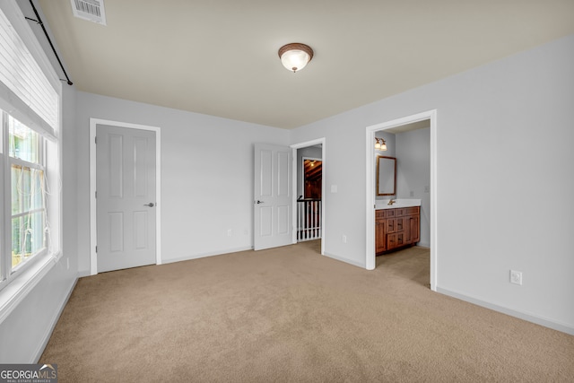 unfurnished bedroom featuring a closet, light colored carpet, and connected bathroom