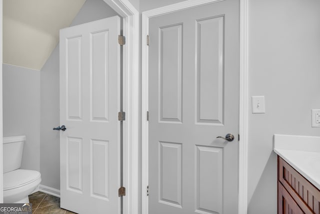 bathroom featuring vaulted ceiling, tile patterned floors, vanity, and toilet