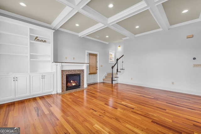 unfurnished living room with crown molding, coffered ceiling, light hardwood / wood-style flooring, and beam ceiling