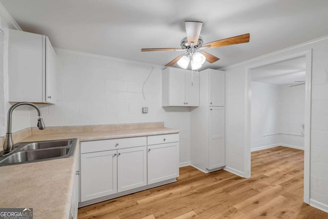 kitchen featuring ceiling fan, sink, white cabinetry, crown molding, and light hardwood / wood-style floors