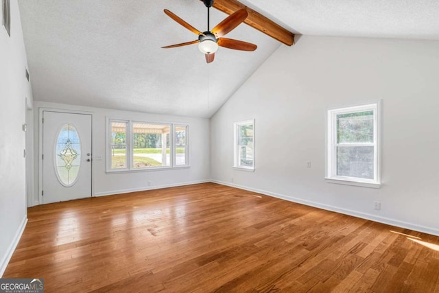 unfurnished living room featuring high vaulted ceiling, beamed ceiling, ceiling fan, light hardwood / wood-style floors, and a textured ceiling