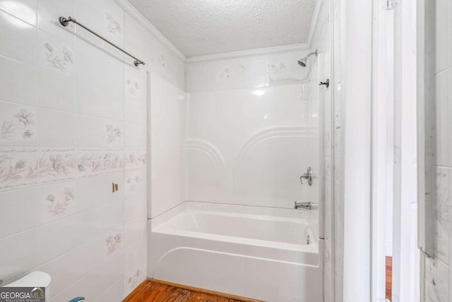 bathroom with ornamental molding, hardwood / wood-style floors, shower / washtub combination, and a textured ceiling