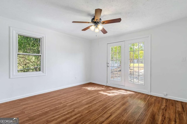 spare room with a textured ceiling, plenty of natural light, wood-type flooring, and ceiling fan