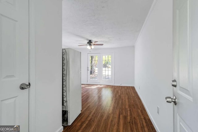 corridor featuring ornamental molding, a textured ceiling, french doors, and dark hardwood / wood-style flooring