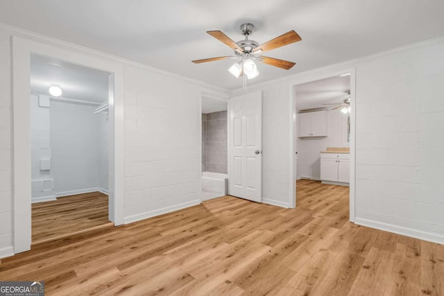 unfurnished bedroom featuring crown molding, ensuite bathroom, and light wood-type flooring