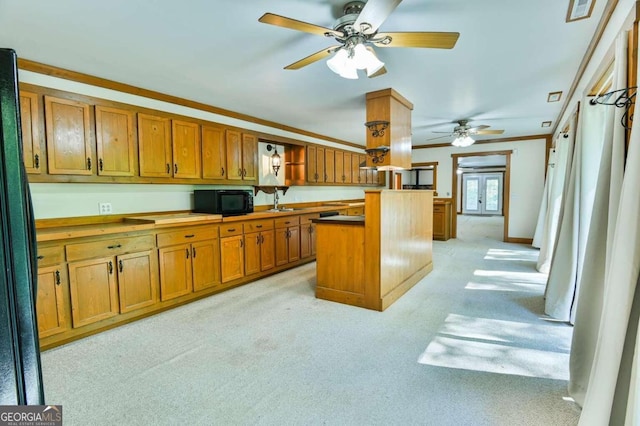 kitchen featuring light carpet, french doors, black appliances, ornamental molding, and a center island