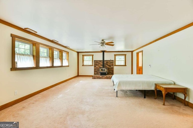 carpeted bedroom with a wood stove, crown molding, and ceiling fan