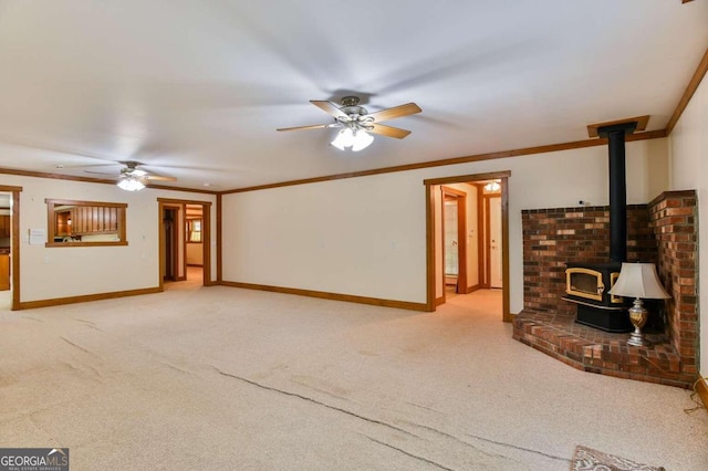 unfurnished living room with ornamental molding, light carpet, a wood stove, and ceiling fan