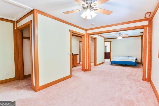 unfurnished bedroom with a closet, light colored carpet, crown molding, and ceiling fan