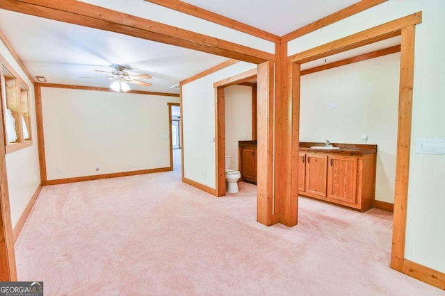 unfurnished room featuring ceiling fan, light colored carpet, crown molding, and sink