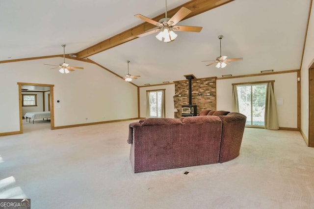 carpeted living room with ornamental molding, lofted ceiling with beams, and a wood stove