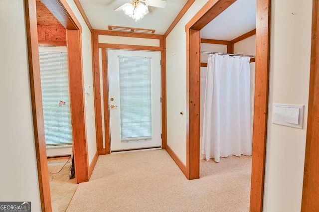 corridor with crown molding and light colored carpet