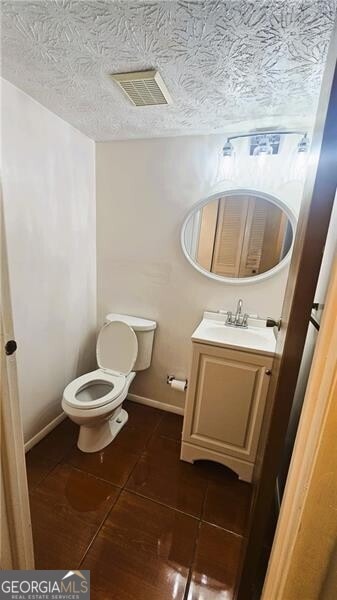 bathroom featuring vanity, a textured ceiling, toilet, and tile patterned flooring