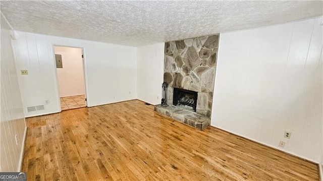 unfurnished living room featuring hardwood / wood-style floors, a fireplace, and a textured ceiling