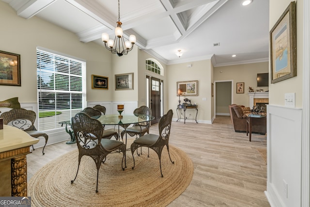 dining room featuring light hardwood / wood-style floors, beamed ceiling, an inviting chandelier, coffered ceiling, and ornamental molding