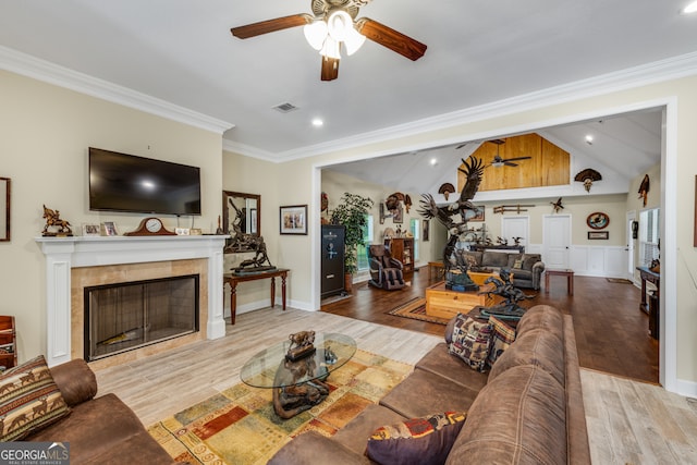 living room with light hardwood / wood-style flooring, crown molding, vaulted ceiling, and a fireplace