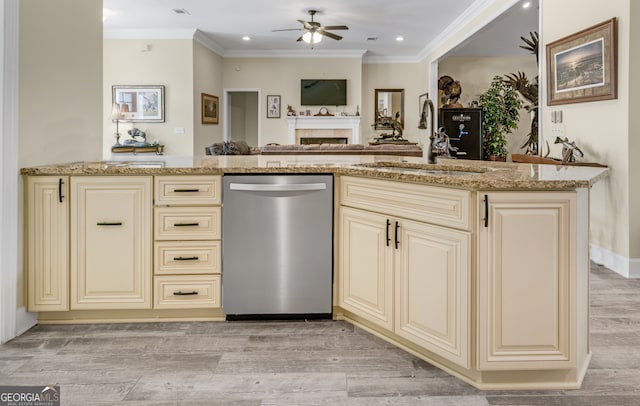 kitchen with light stone counters, cream cabinets, sink, and stainless steel dishwasher