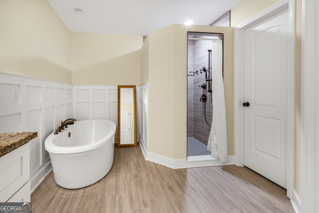 bathroom with plus walk in shower, hardwood / wood-style floors, and vanity