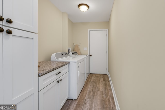 laundry room with light wood-type flooring, washing machine and clothes dryer, and cabinets