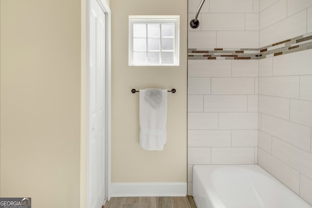 bathroom with hardwood / wood-style floors and tiled shower / bath combo