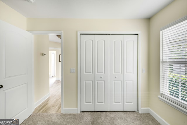 unfurnished bedroom with light colored carpet and a closet