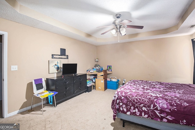 bedroom featuring carpet, a tray ceiling, a textured ceiling, and ceiling fan