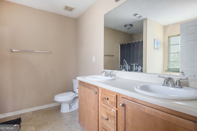 bathroom with a textured ceiling, toilet, vanity, curtained shower, and tile patterned flooring