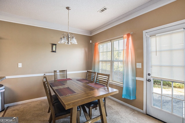 carpeted dining space with a textured ceiling, ornamental molding, and a chandelier