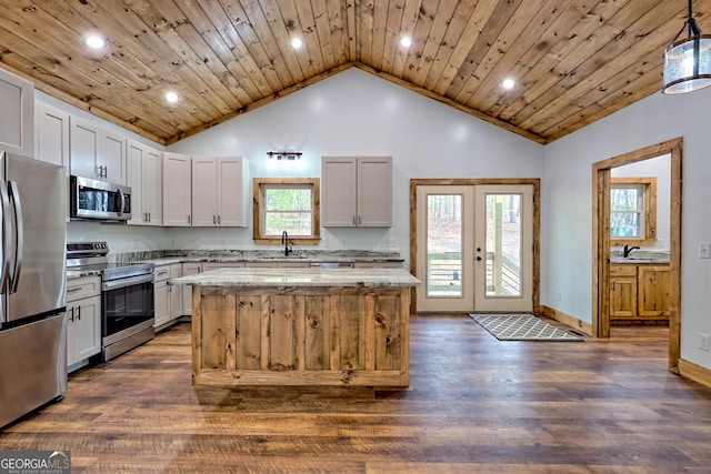 kitchen with a healthy amount of sunlight, white cabinetry, stainless steel appliances, and hanging light fixtures