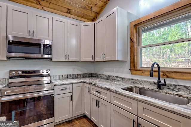 kitchen with wooden ceiling, white cabinets, sink, vaulted ceiling, and stainless steel appliances