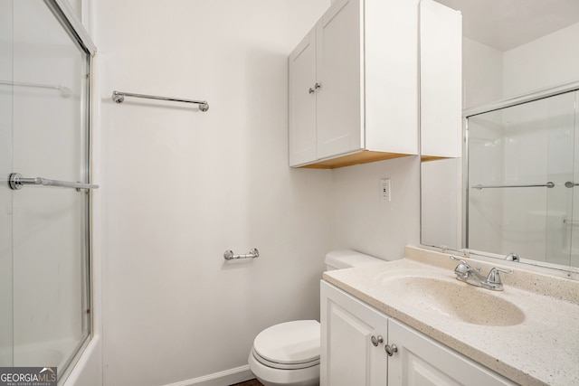 full bathroom featuring vanity, bath / shower combo with glass door, and toilet