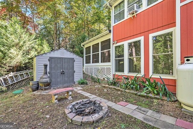 view of patio with a sunroom, a storage shed, and a fire pit