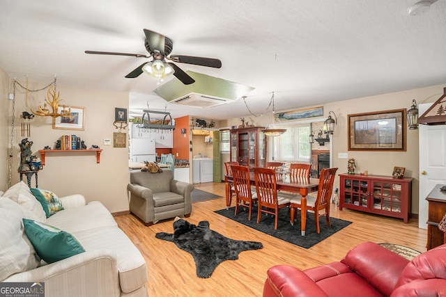 living room with light hardwood / wood-style flooring, independent washer and dryer, a textured ceiling, and ceiling fan