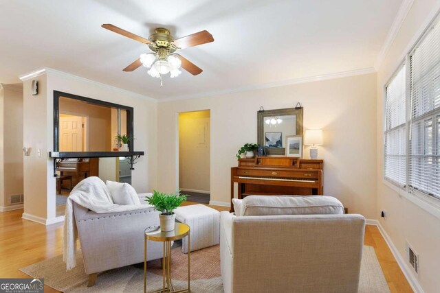 living room featuring ornamental molding, light hardwood / wood-style floors, and ceiling fan